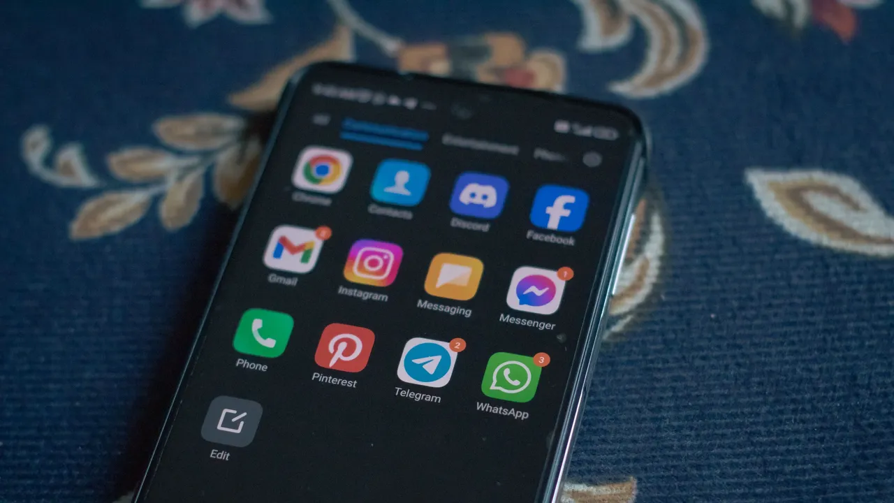Smartfon z ikonami aplikacji, w tym Discorda, Facebooka i Messengera, leżący na granatowym obrusie